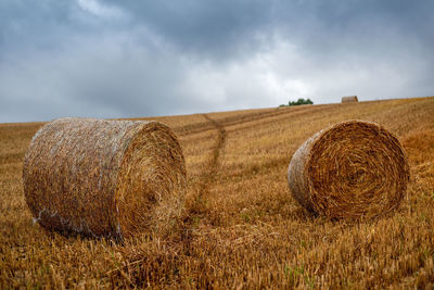 Hay bales on field against sky