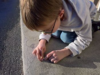High angle view of boy playing with insect on sidewalk