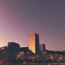 Illuminated buildings in city against sky during sunset