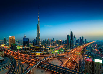 High angle view of illuminated cityscape against clear blue sky