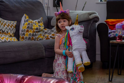 Full length of girl playing with a cardbox unicorn