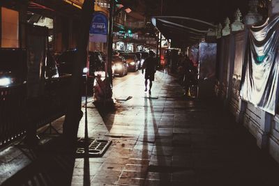 People walking on illuminated street in city at night