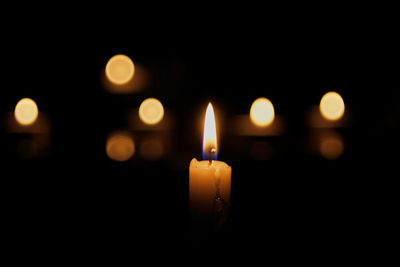 Burning candle on a dark background with light bokeh circles behind