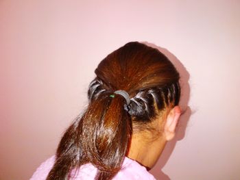 Close-up of woman with braided hairstyle against pink wall