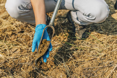 Low section of agronomist analyzing soil on field