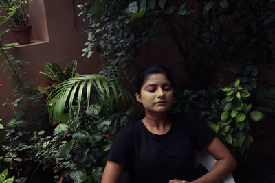 Portrait of woman standing against plants