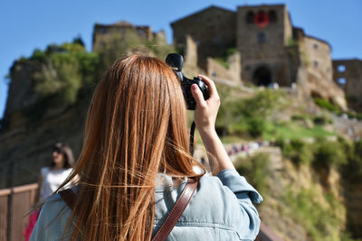 Rear view of woman photographing historic building