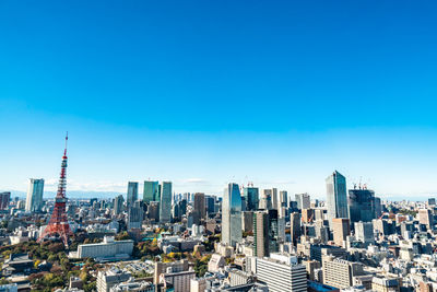 Aerial view of buildings in city against blue sky