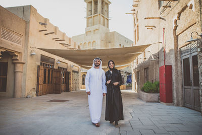 Full length of smiling couple talking while walking on street in town