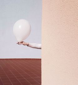 Midsection of woman holding balloons against wall