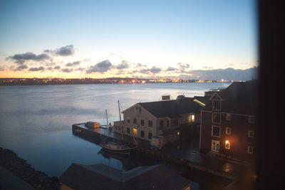 Buildings by sea against sky at sunset