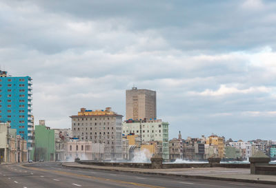 Road by buildings against sky in city