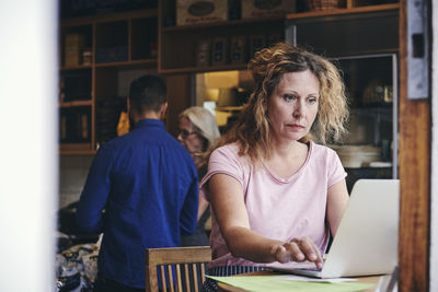 Mature saleswoman using laptop at table in deli