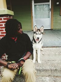 Portrait of woman with dog sitting on house at home