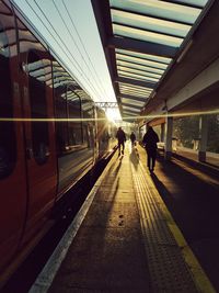 Early morning at train station with commuters silhoutted by winter sun