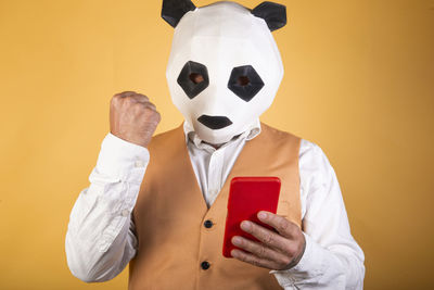 Man in suit and panda mask using a smartphone