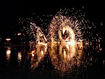 Firework display over lake against sky at night