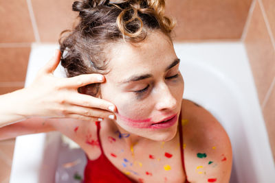 Woman smudging paint on face in bathroom