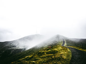 Scenic view of mountains in foggy weather against sky