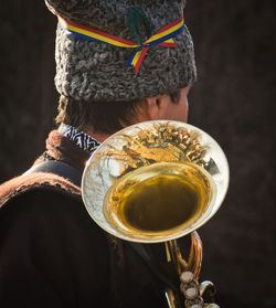 Close-up of man holding musical instrument against black background