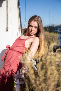 Portrait of young woman standing against sky