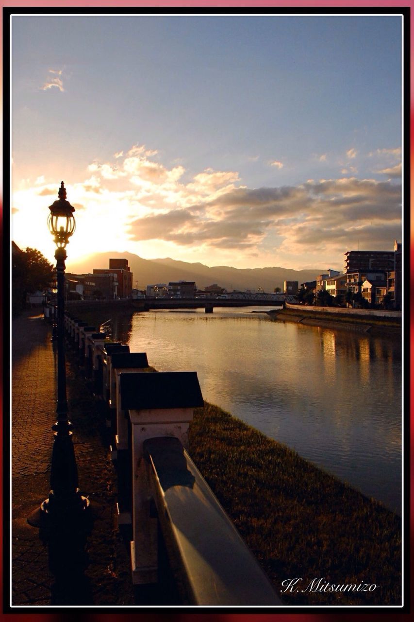 transfer print, water, auto post production filter, built structure, architecture, sky, building exterior, sunset, river, railing, bridge - man made structure, city, transportation, cloud - sky, pier, street light, outdoors, sea, sunlight, cloud