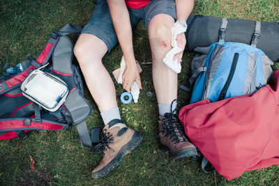 Low section of person cleaning wound on grassy field