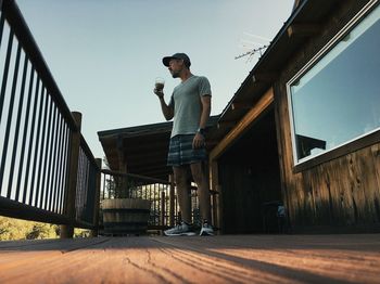 Full length of man standing on railing against sky