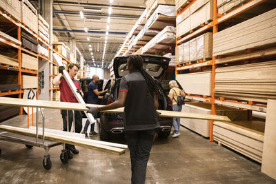 Sales staff helping customers loading planks at hardware store