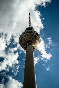 Low angle view of communications tower against cloudy sky