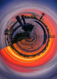 Digital composite image of illuminated city against sky during sunset