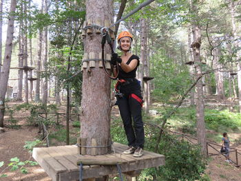 Portrait of happy woman preparing for zip lining in forest