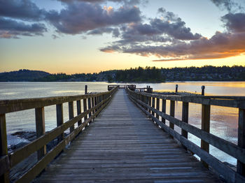 Pier over lake against sky during sunset