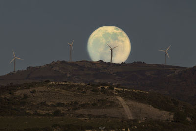 Wind turbines on field against sky