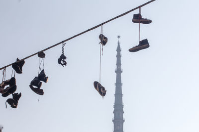 Low angle view of shoes hanging on cable against historical building