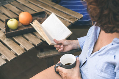 High angle view of woman reading book while sitting outdoors