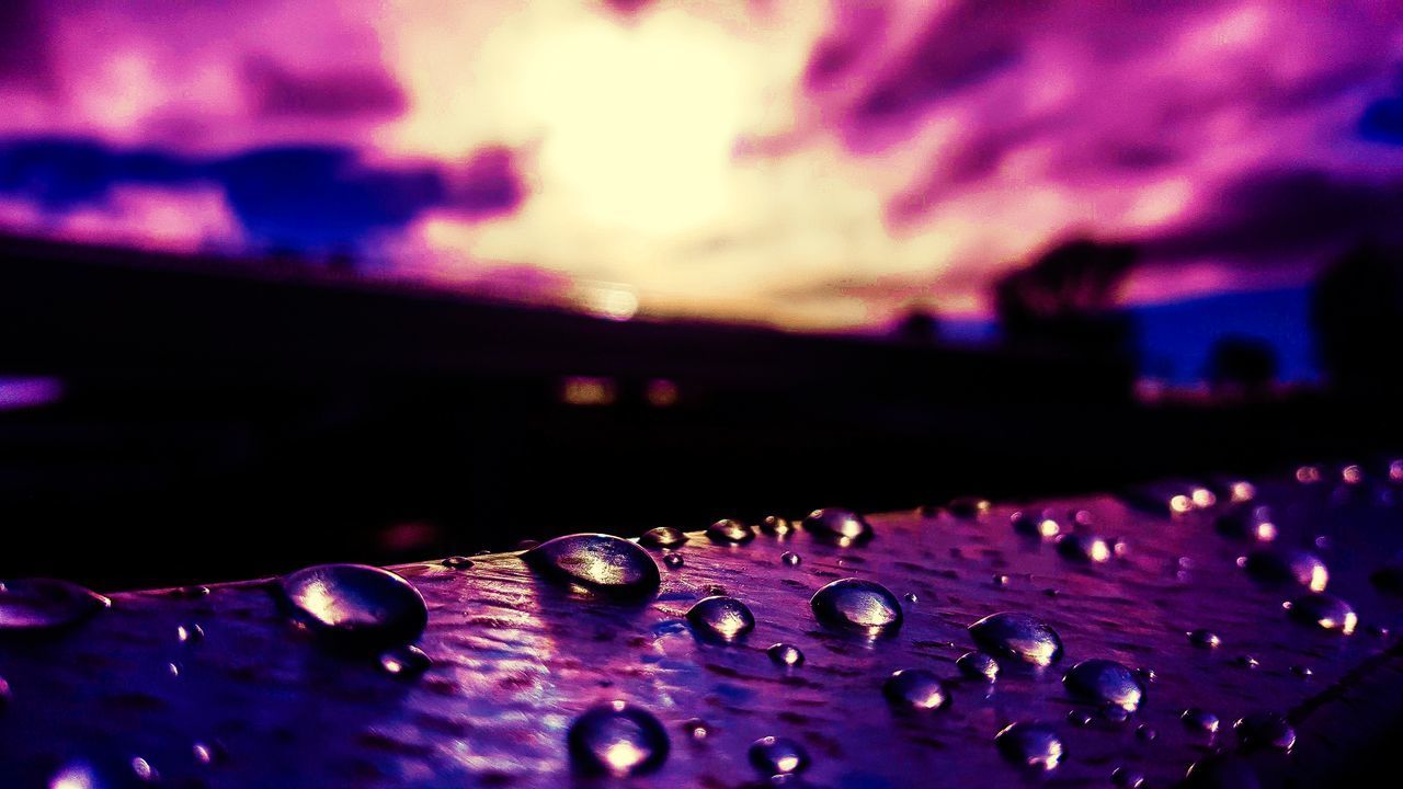 CLOSE-UP OF WATER DROPS ON PURPLE SURFACE