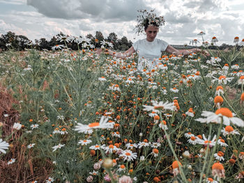 Woman standing by flowering plants on field