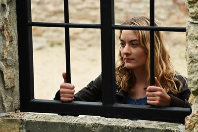 Portrait of young woman looking through window