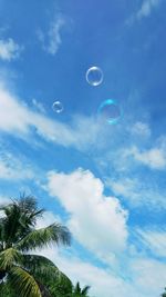 Low angle view of bubbles against blue sky