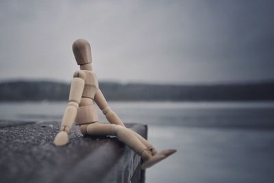 Close-up of mannequin on beach against sky