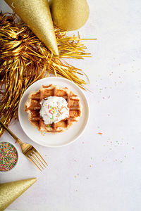 Birthday party waffles decorated with youghurt and colorful sprinkles, top view flat lay