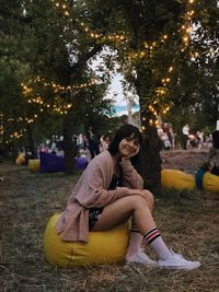 Portrait of young woman sitting on bean bag over field