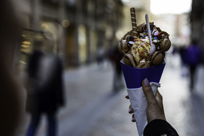 Close-up of hand holding ice cream cone on street