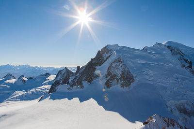 Sun shining over snow covered mountains