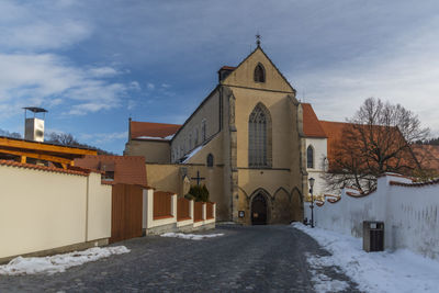 Road amidst buildings against sky during winter