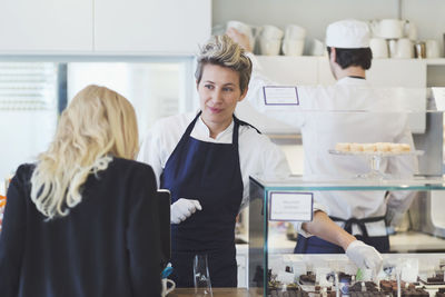 Female cafe worker attending customer at counter