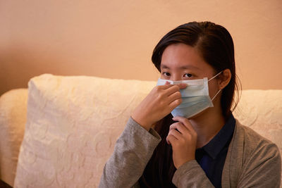 Portrait of a woman adjusting her face mask  at home