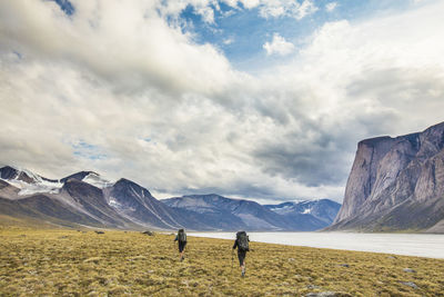 Rear view of backpackers hiking on baffin island, canada.