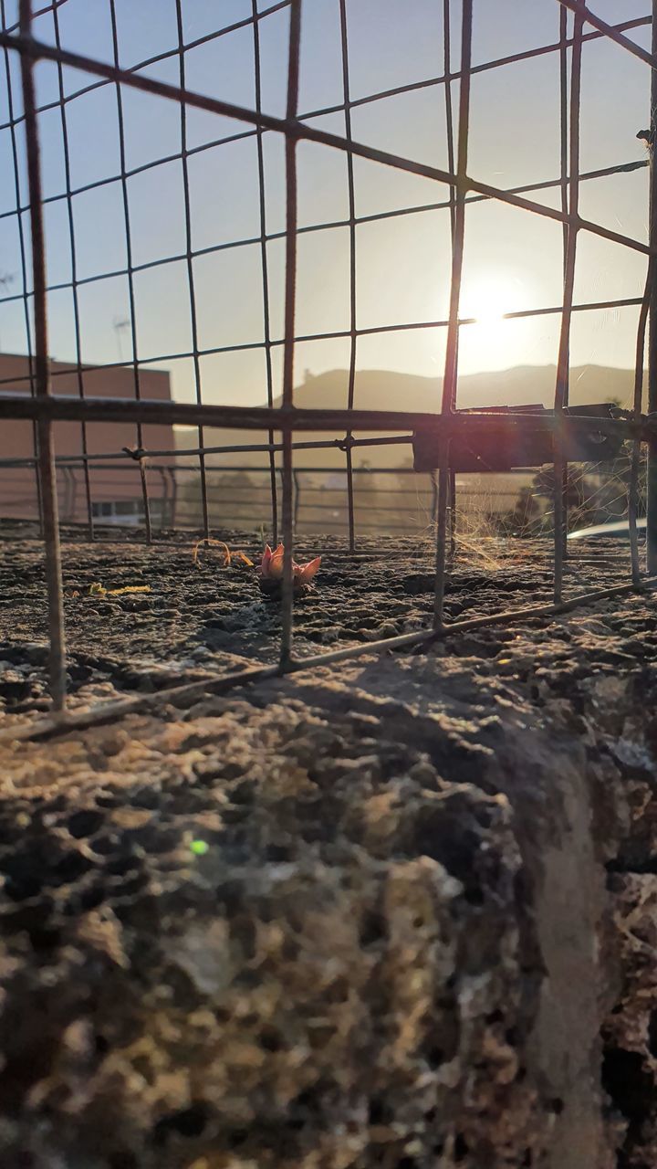 sky, nature, sunlight, no people, sunset, land, built structure, outdoors, field, architecture, selective focus, day, metal, sun, barrier, lens flare, fence, construction industry, boundary, environment, surface level